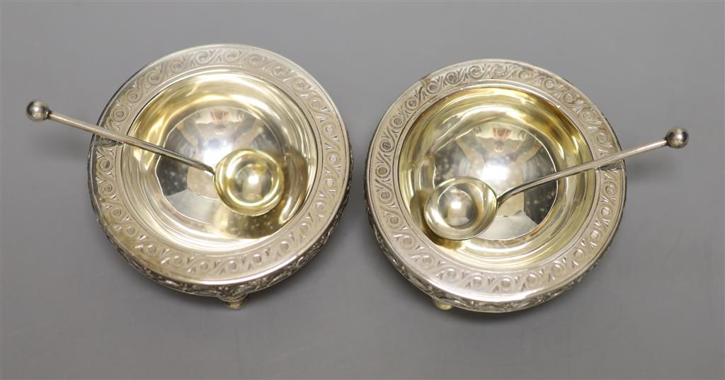 A pair of Victorian silver circular salts and matching spoons, on tripod stump feet, The Barnards, London, 1874,